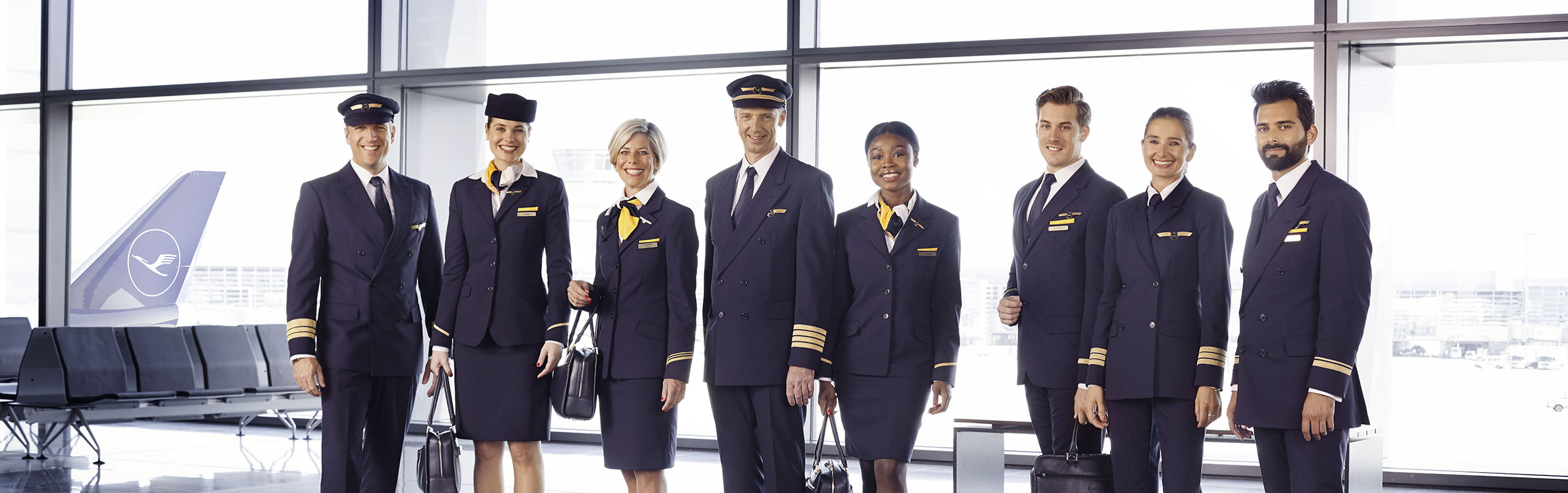 Three men and four women of different origins in the dark blue Lufthansa uniform